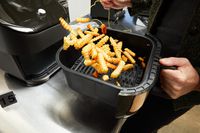 A person tossing fries in the Instant Pot Vortex Plus 6-Quart ClearCook Air Fryer