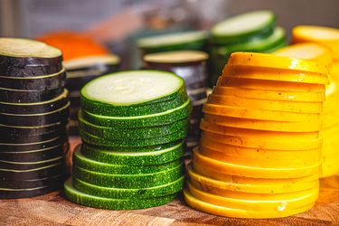 Stacked slices of green zucchini and yellow squash on a cutting board, arranged neatly