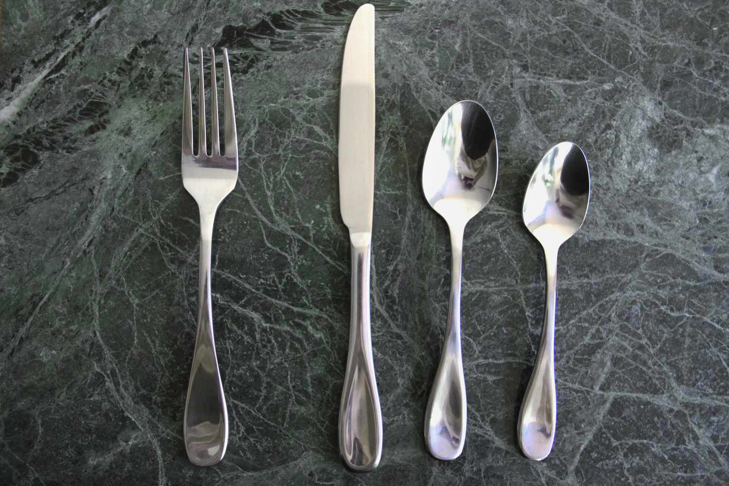 A set of flatware on a dark marble surface