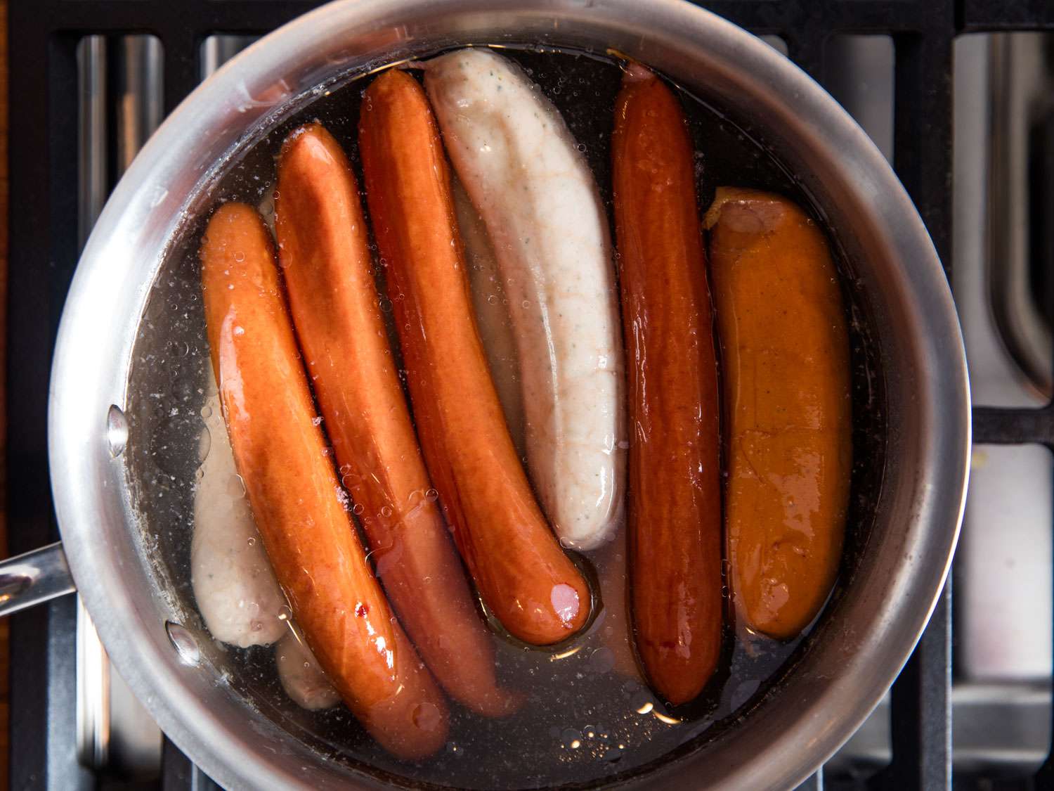 A saucepan filled with simmering sausages for choucroute garnie.