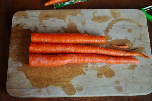 Trimming carrots on a cutting board.