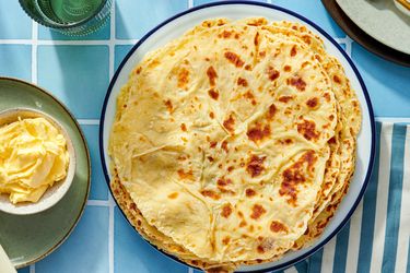 A plate of lefse flatbreads with butter on the side set on a tiled surface