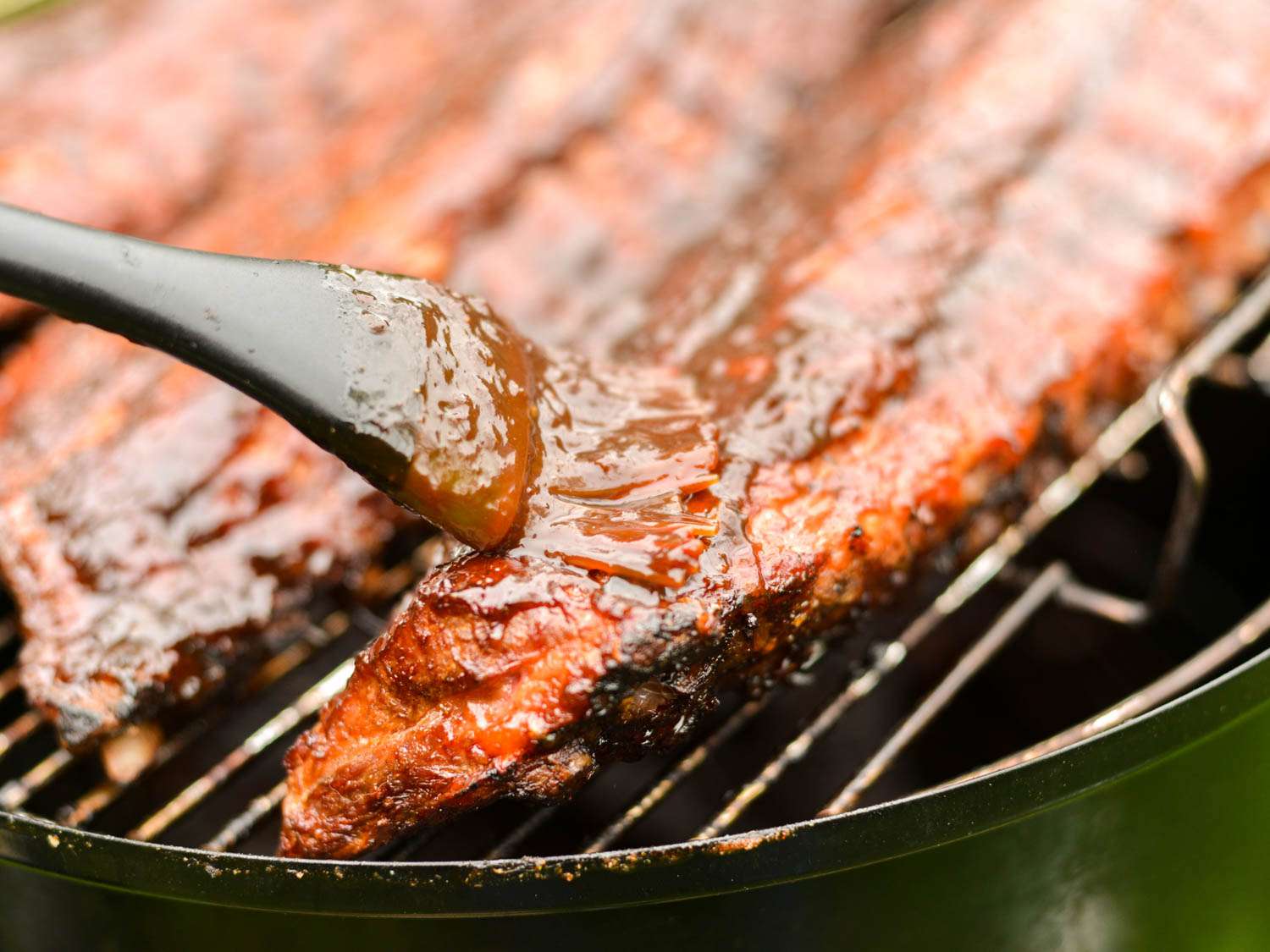 Balsamic barbecue sauce is used to glaze ribs as they cook on the grill.
