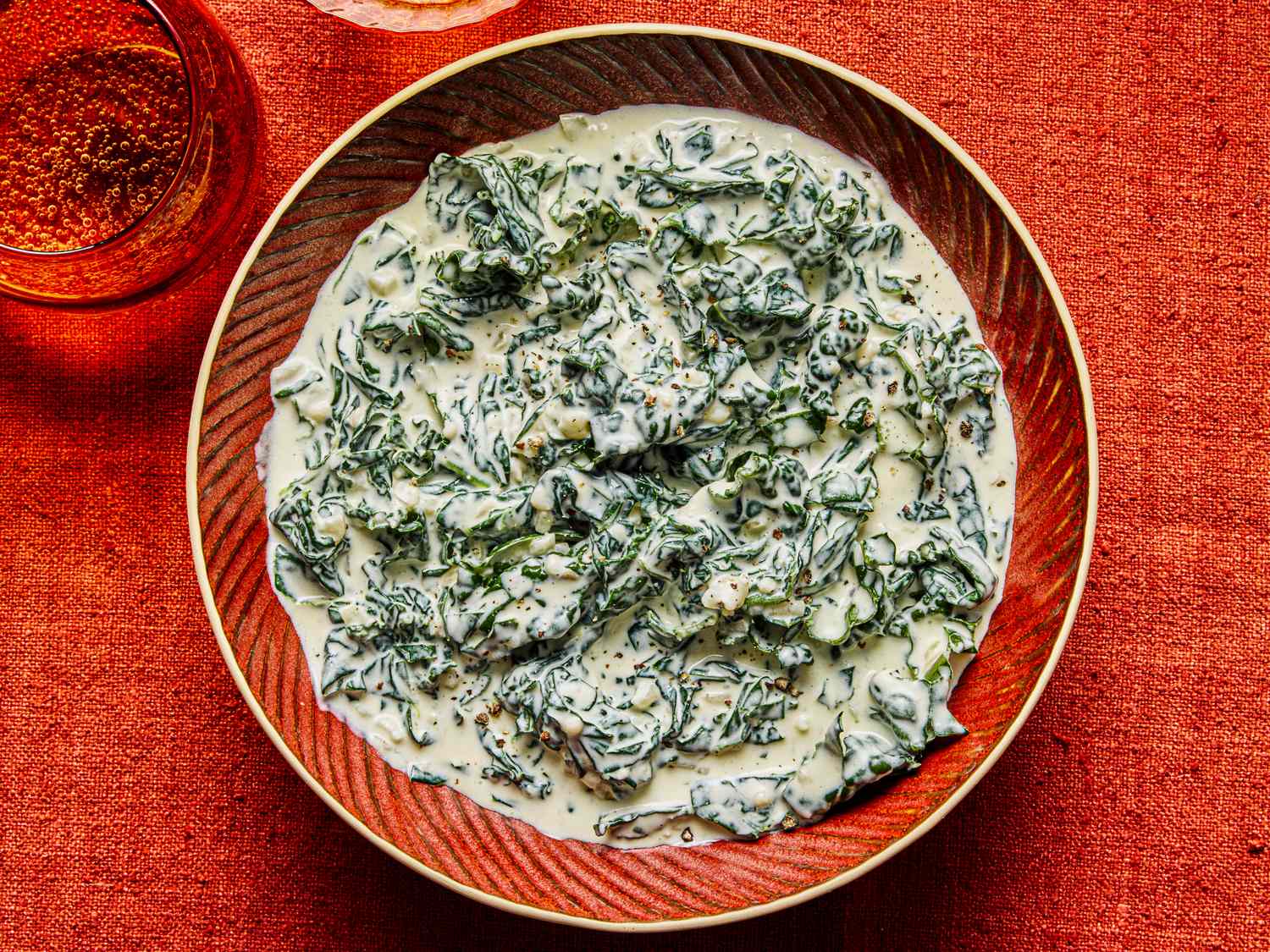 A bowl of creamed kale on a red tablecloth