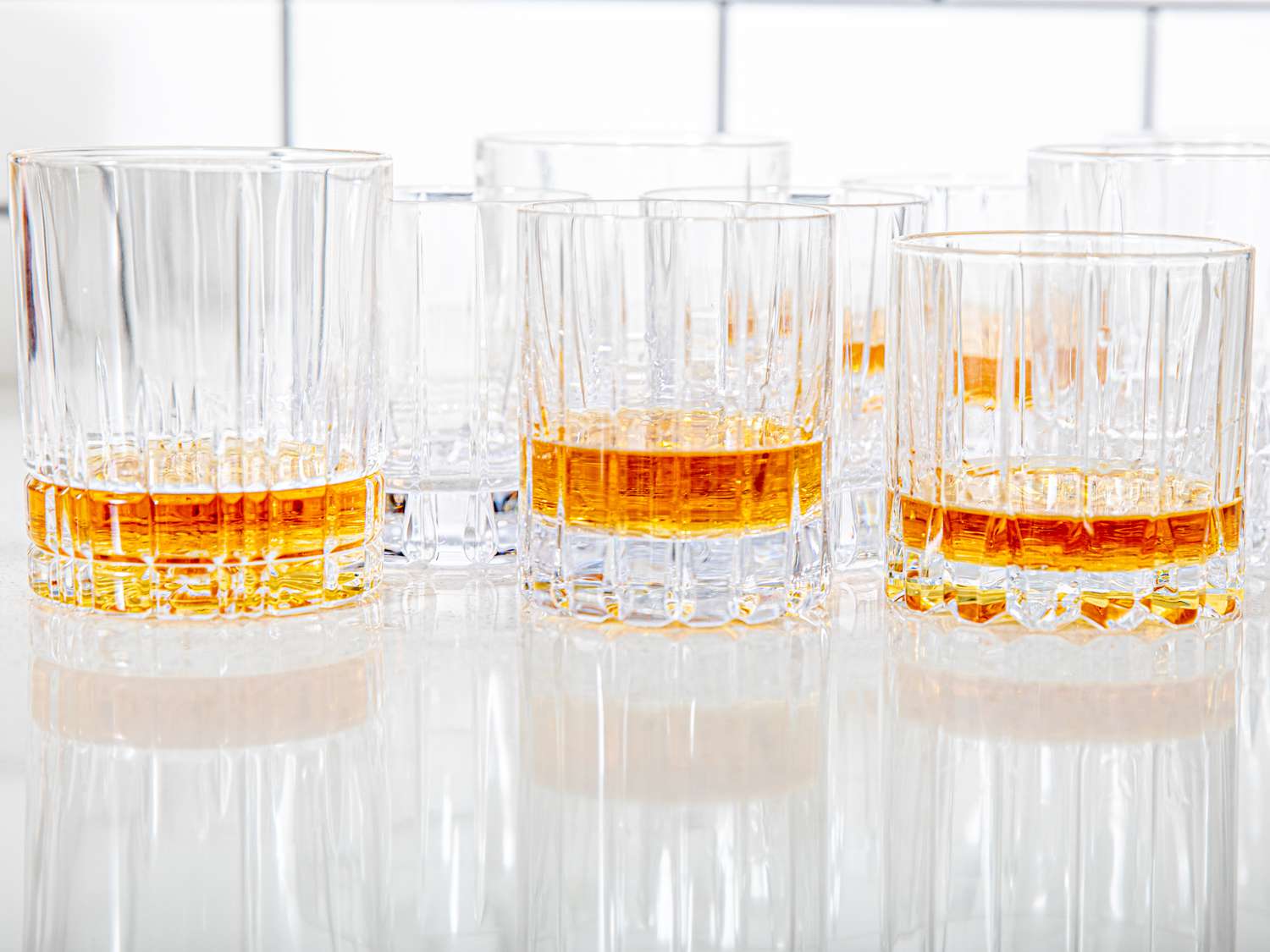 Numerous whiskey rocks glasses on a kitchen countertop