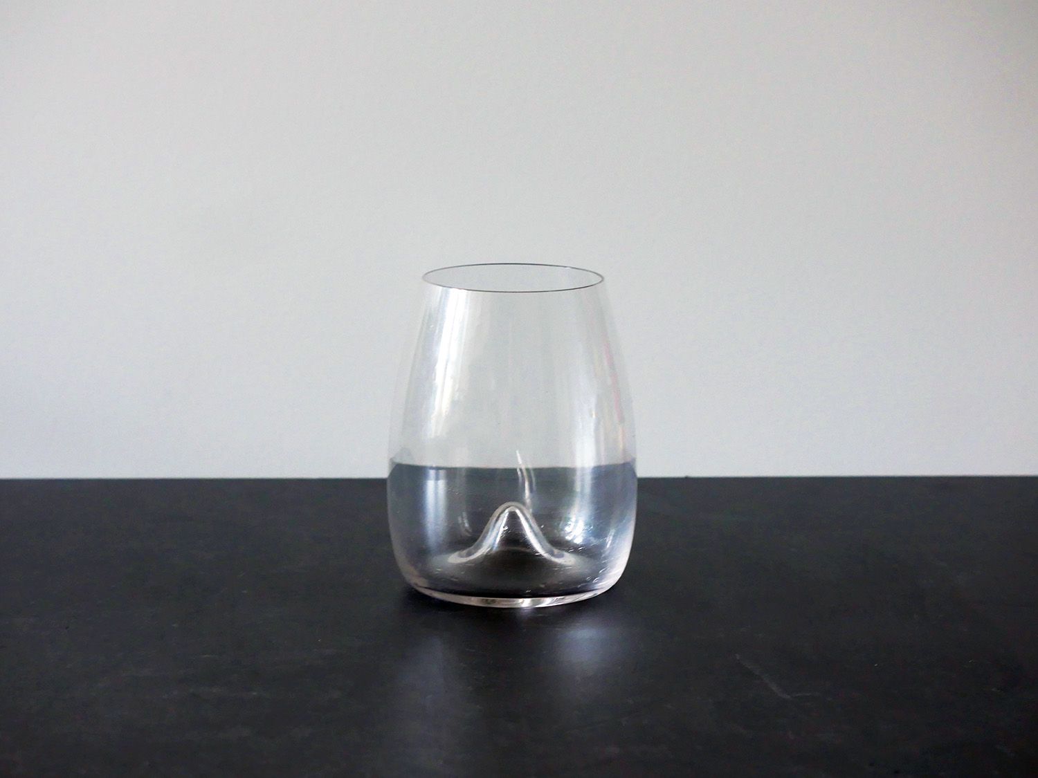 waterford stemless wine glass on black countertop with white backdrop