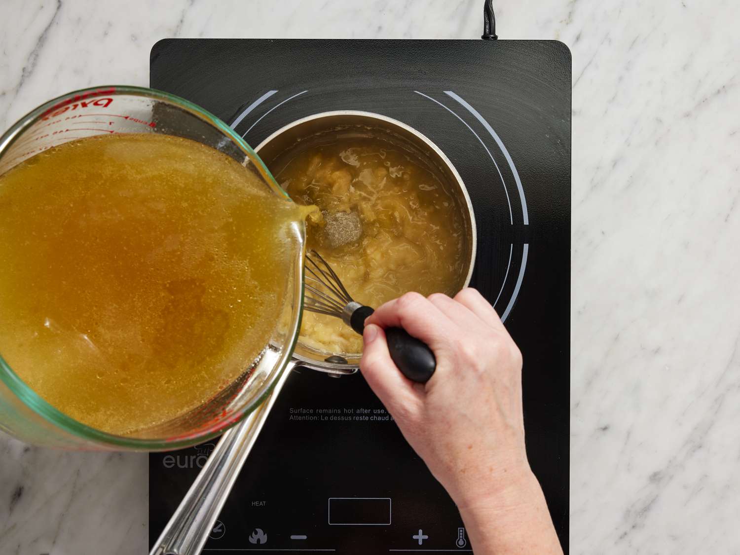 Whisking while adding broth to butter mixture over heat
