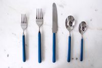 Set of five utensils including forks a knife and spoons on a surface