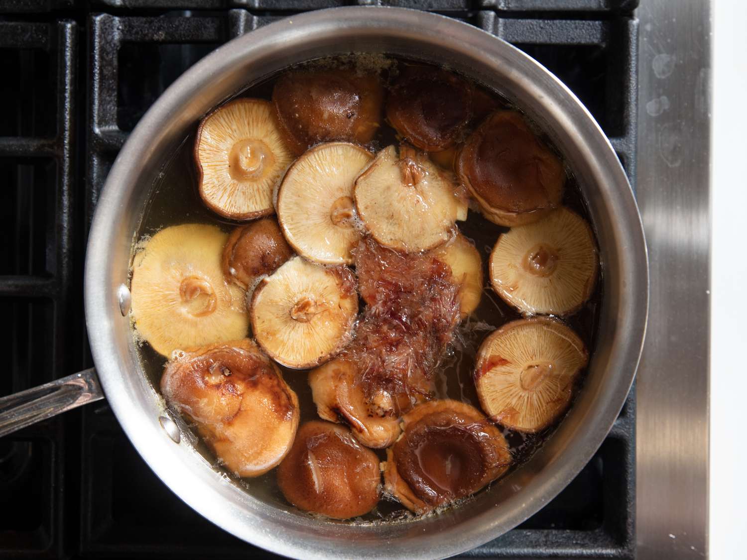 A pot of dried mushrooms, bonito flakes, and kombu simmering to make dashi for ozoni.