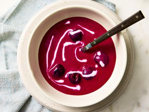 A bowl of beet and cherry soup with a swirl of sour cream