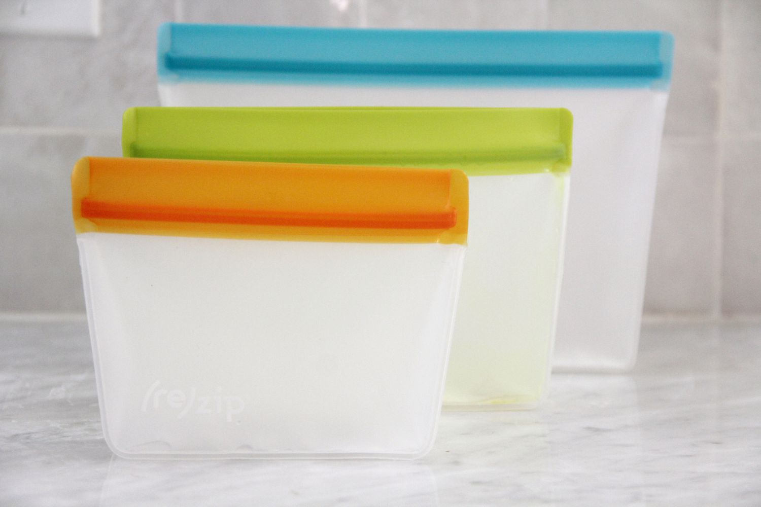 Three reusable food bags on a marble kitchen countertop