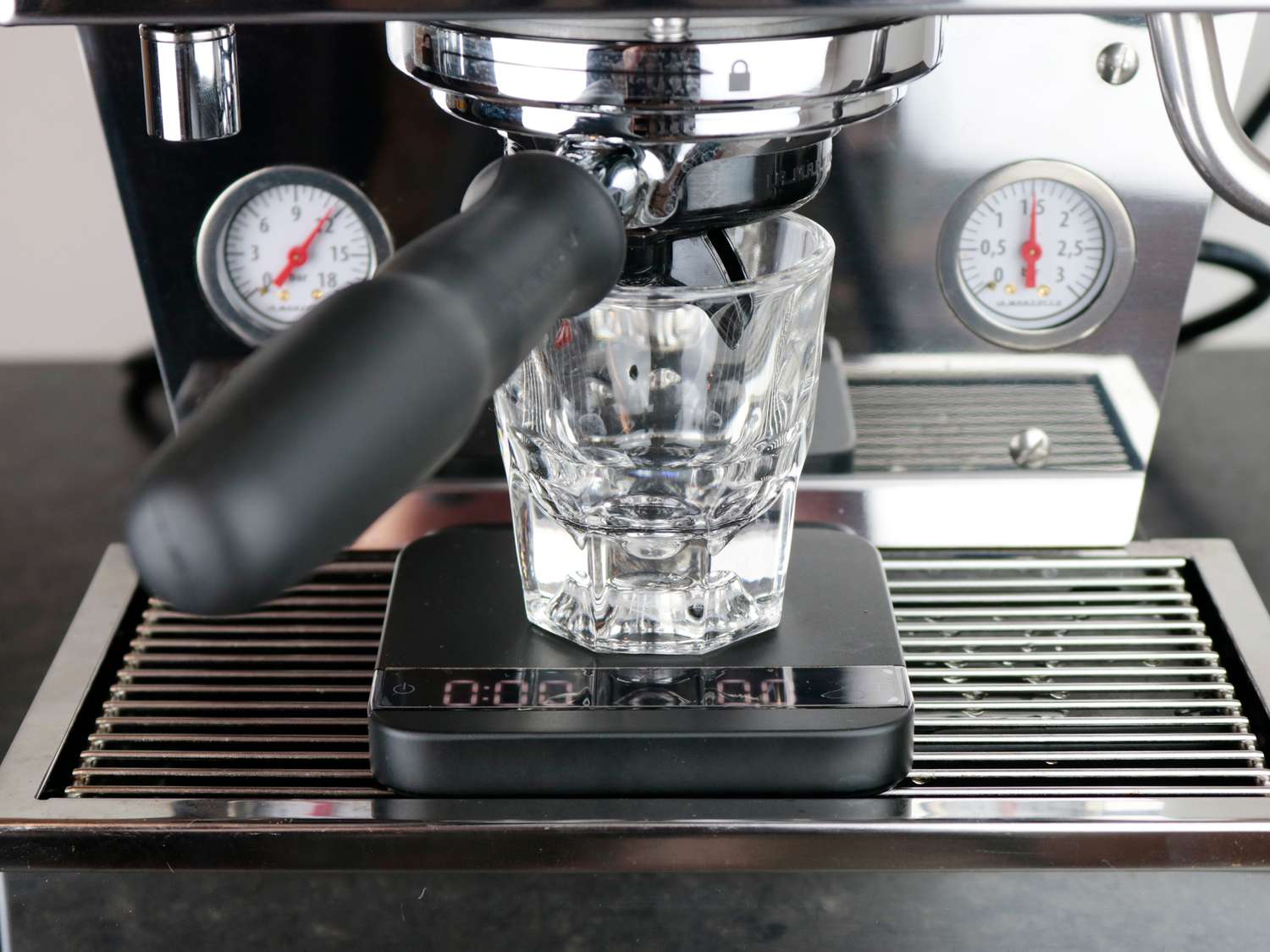 an espresso machine with the portafilter spouts below the lip of a glass