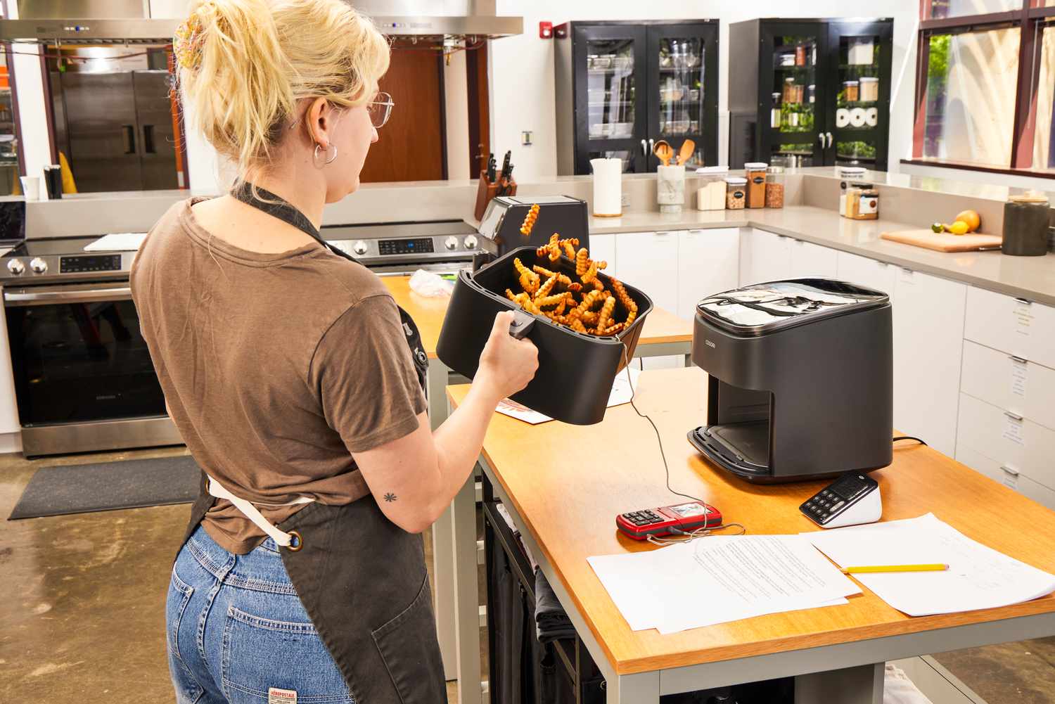 A person tossing fies in the COSORI TurboBlaze 6.0-Quart Air Fryer basket