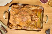 A fully-cooked KellyBronze Turkey in a roasting pan, on a table