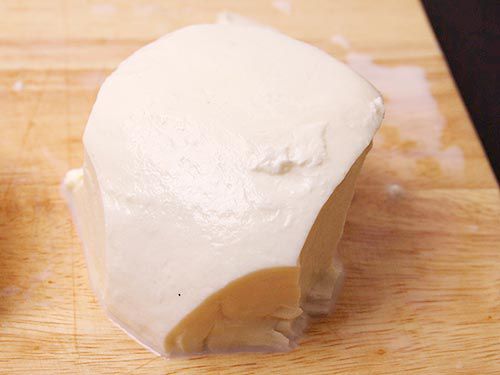 A piece of mozzarella with slices out of it.