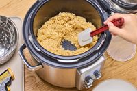 A person stirs rice cooked in the Breville the Fast Slow Pro