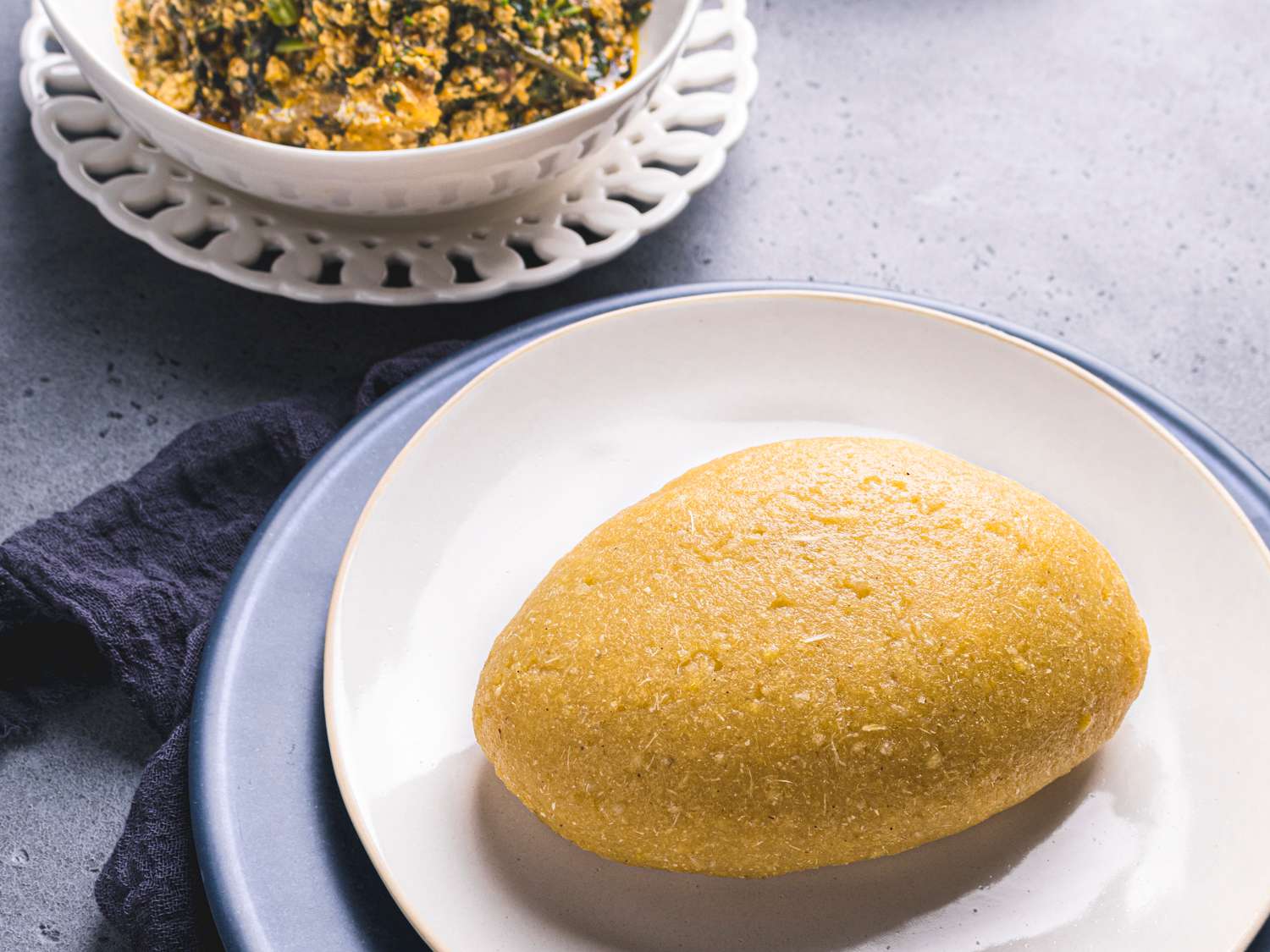 Eba plated next to a bowl of egusi soup