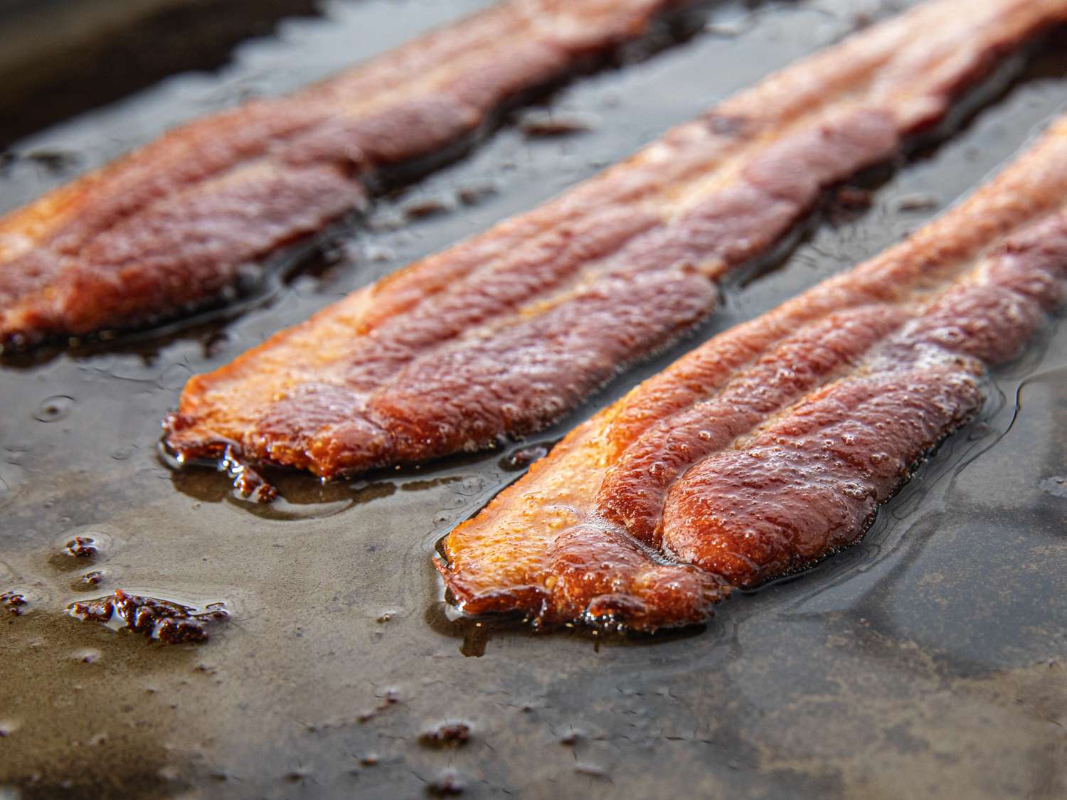 Close up of bacon frying on a griddle