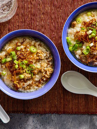 Overhead view of two bowls of congee on a brown woven placemat