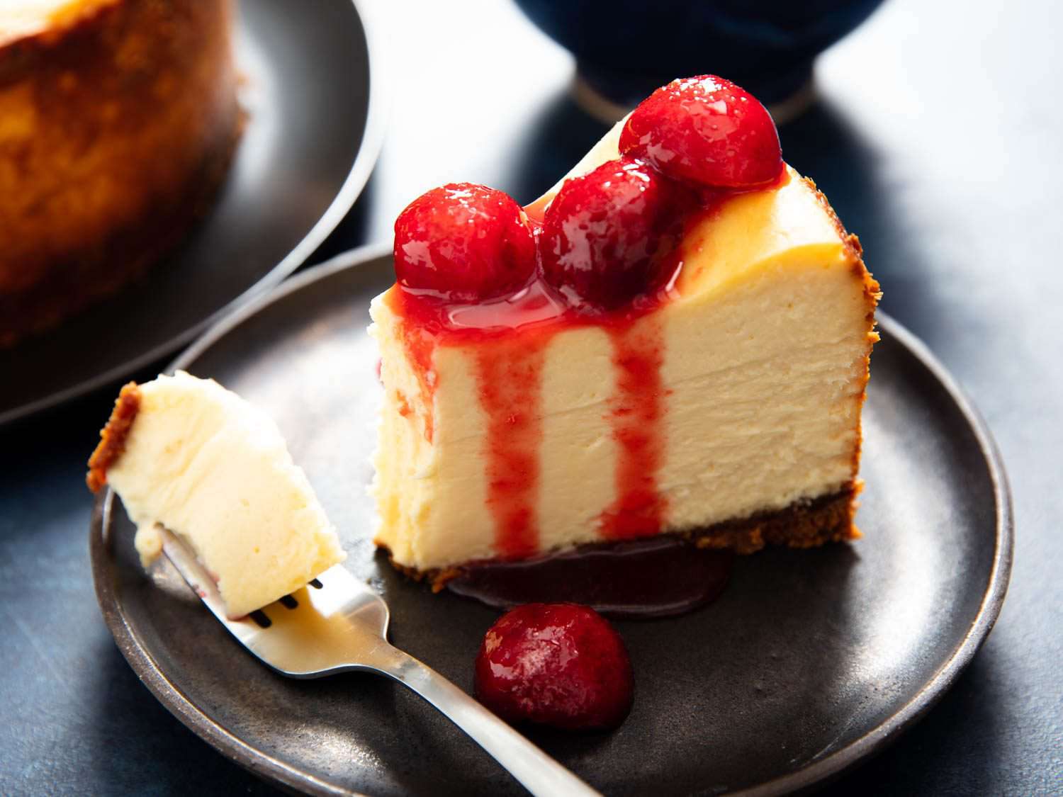 A massive slice of cheesecake with a bite on a fork.