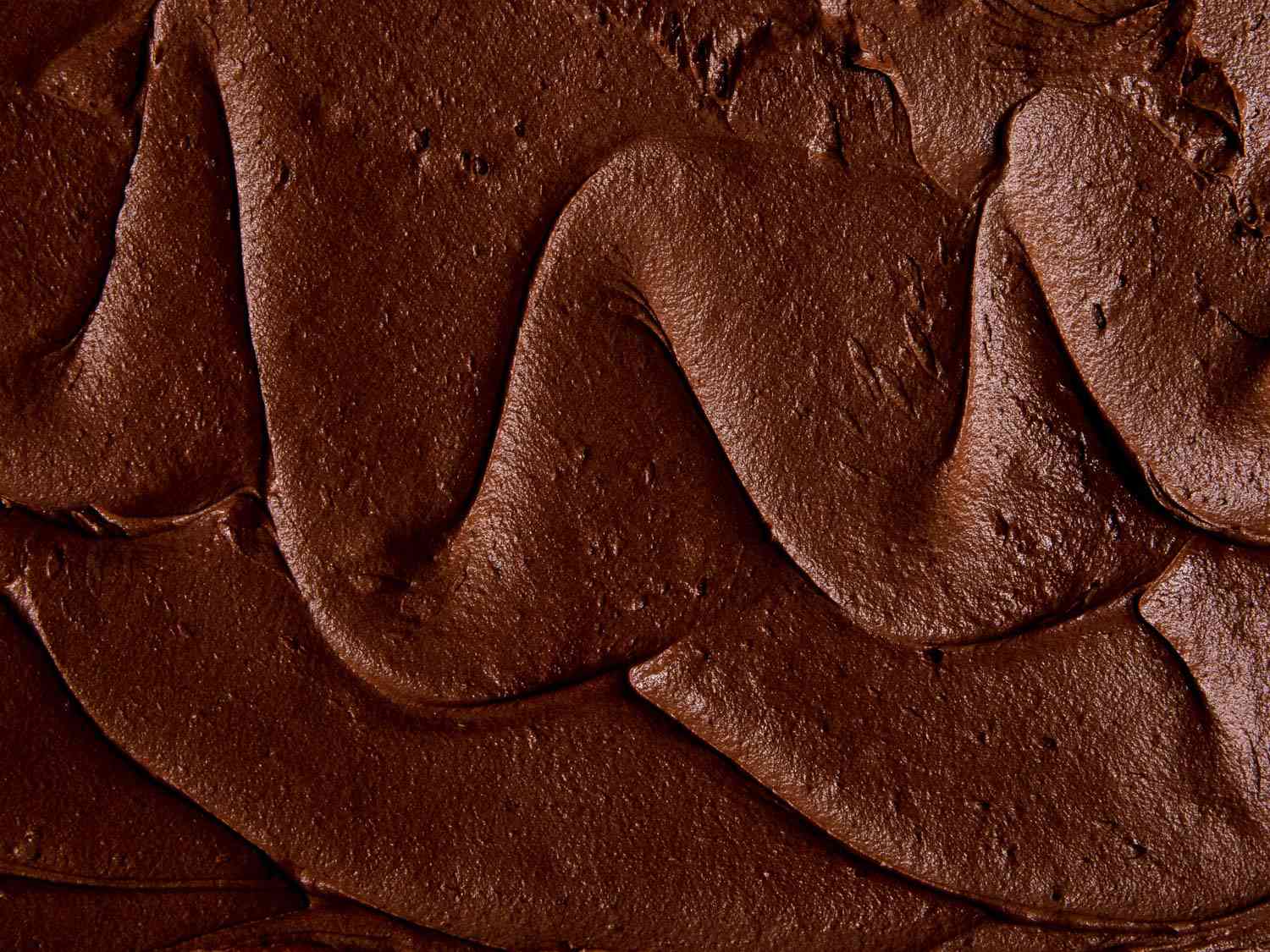 Close-up of the wavy surface of a batch of American-style chocolate buttercream.