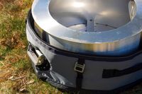 A fire pit partially encased in a padded carrier on grass