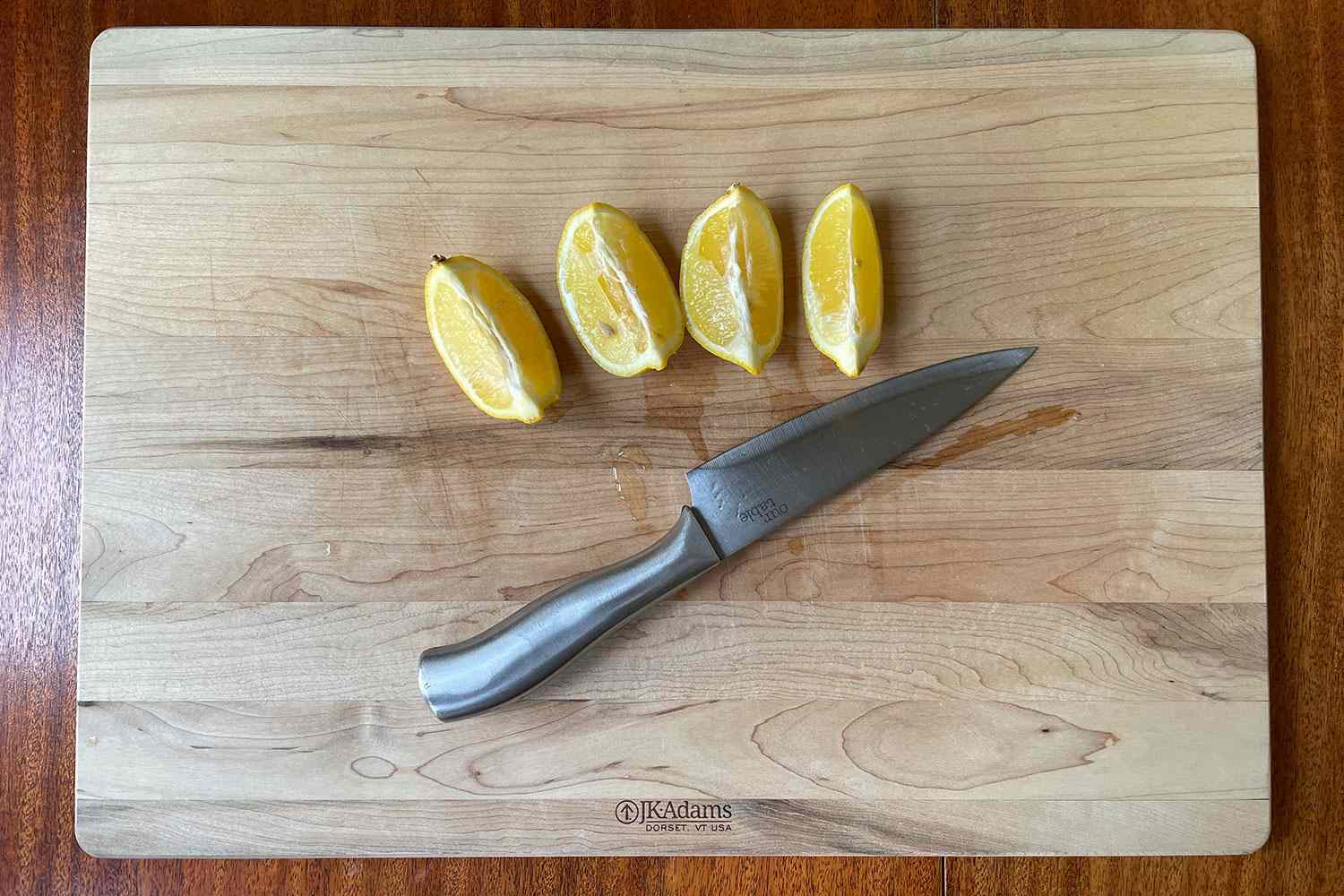 cutting board on counter with lemon wedges and knives