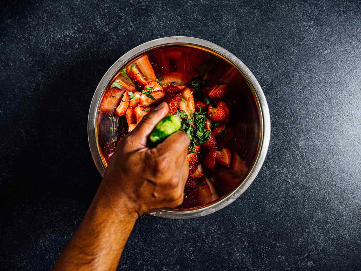 a hand squeezing lime juice into the strawberry mixture