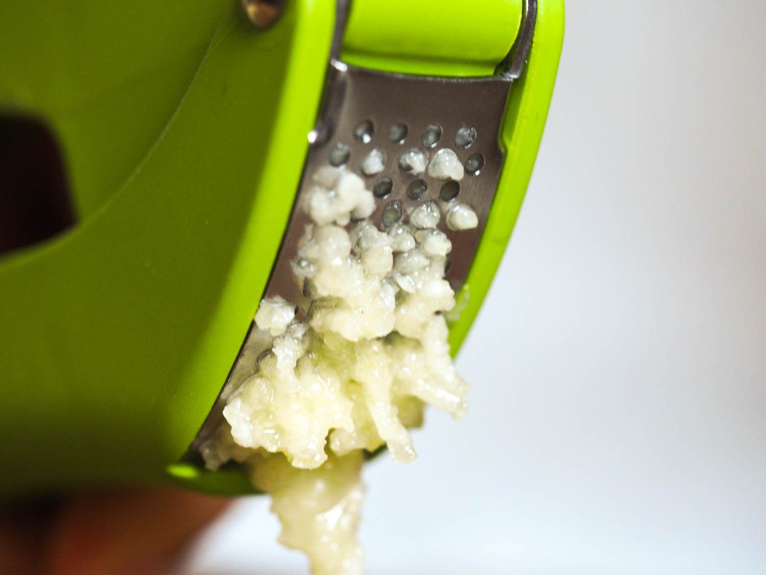 Minced garlic coming out of a garlic press.