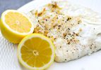 Grilled halibut with two lemon halves on a plate