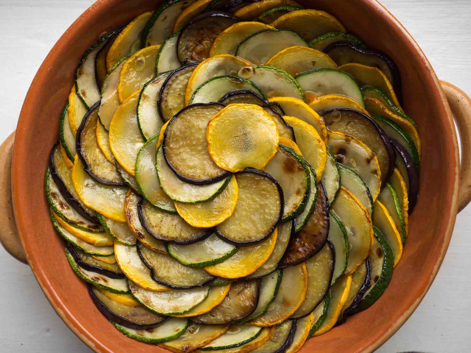 The tian, assembled but without the last addition of tomato sauce. The slices of eggplant, zucchini, and squash have been shingled in a spiral pattern, starting with the outermost ring and working inward.