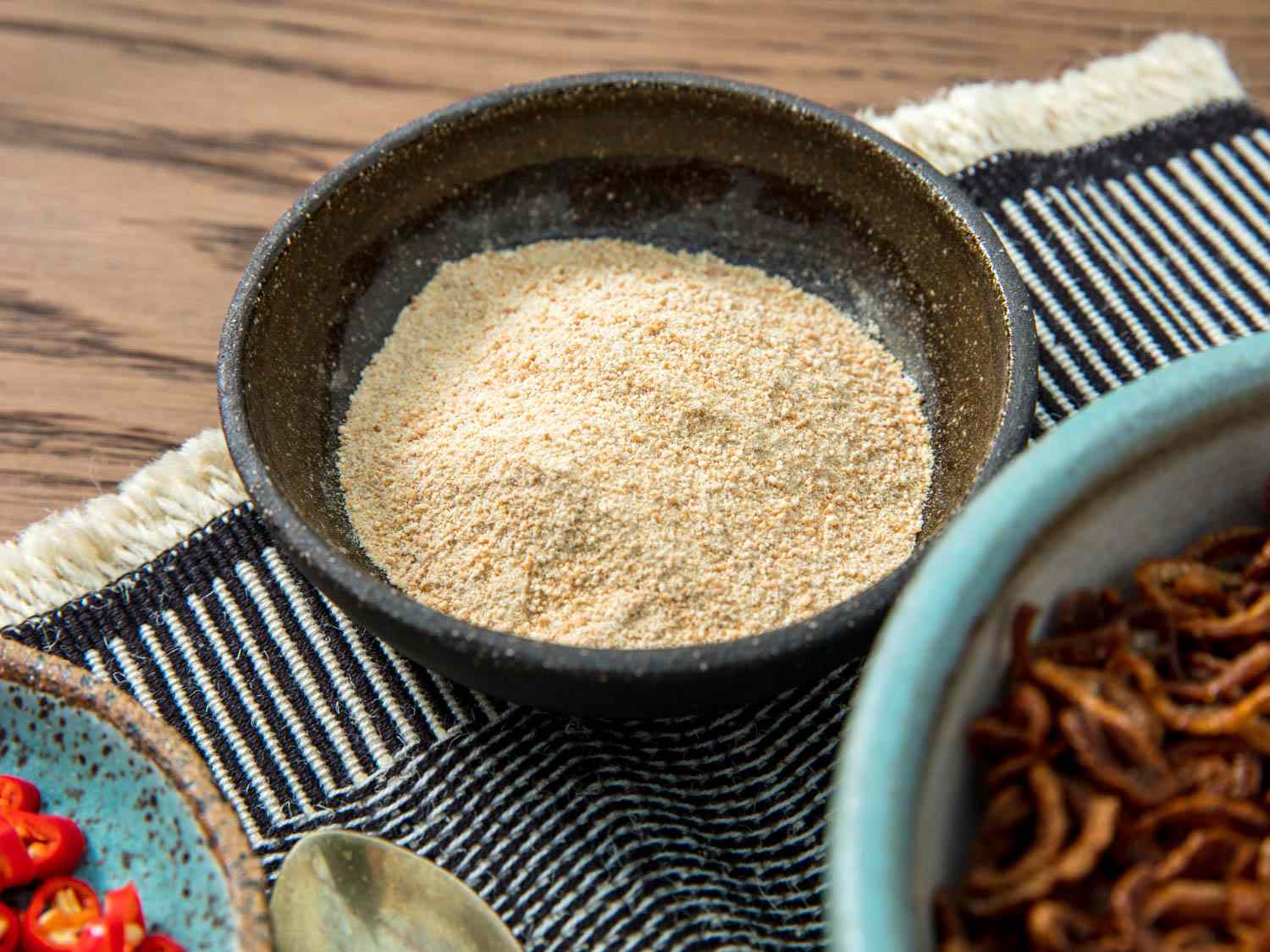 A small bowl of khao khua, or Thai toasted-rice powder, set on a table.
