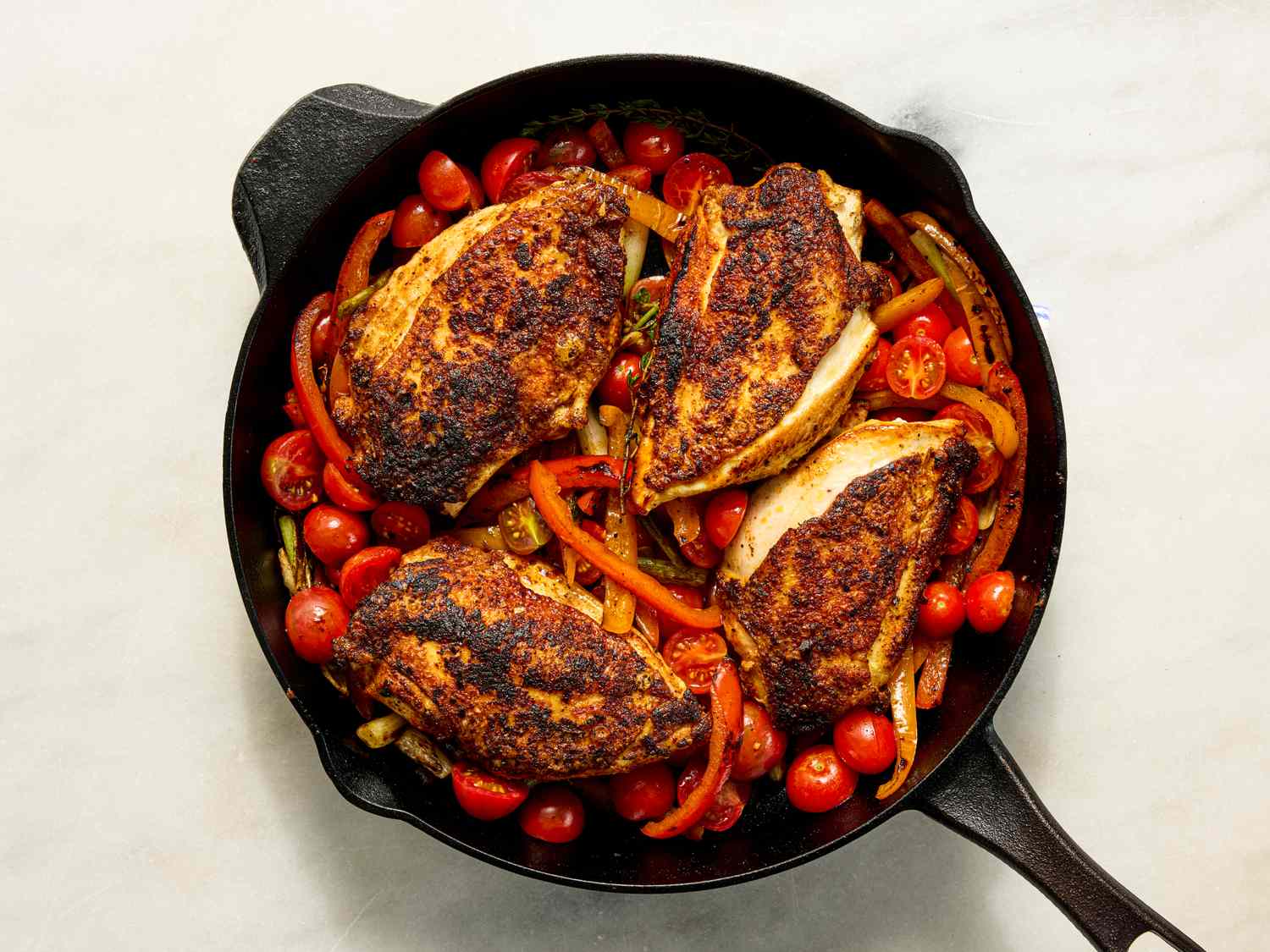 Seared chicken breasts on vegetables in a skillet