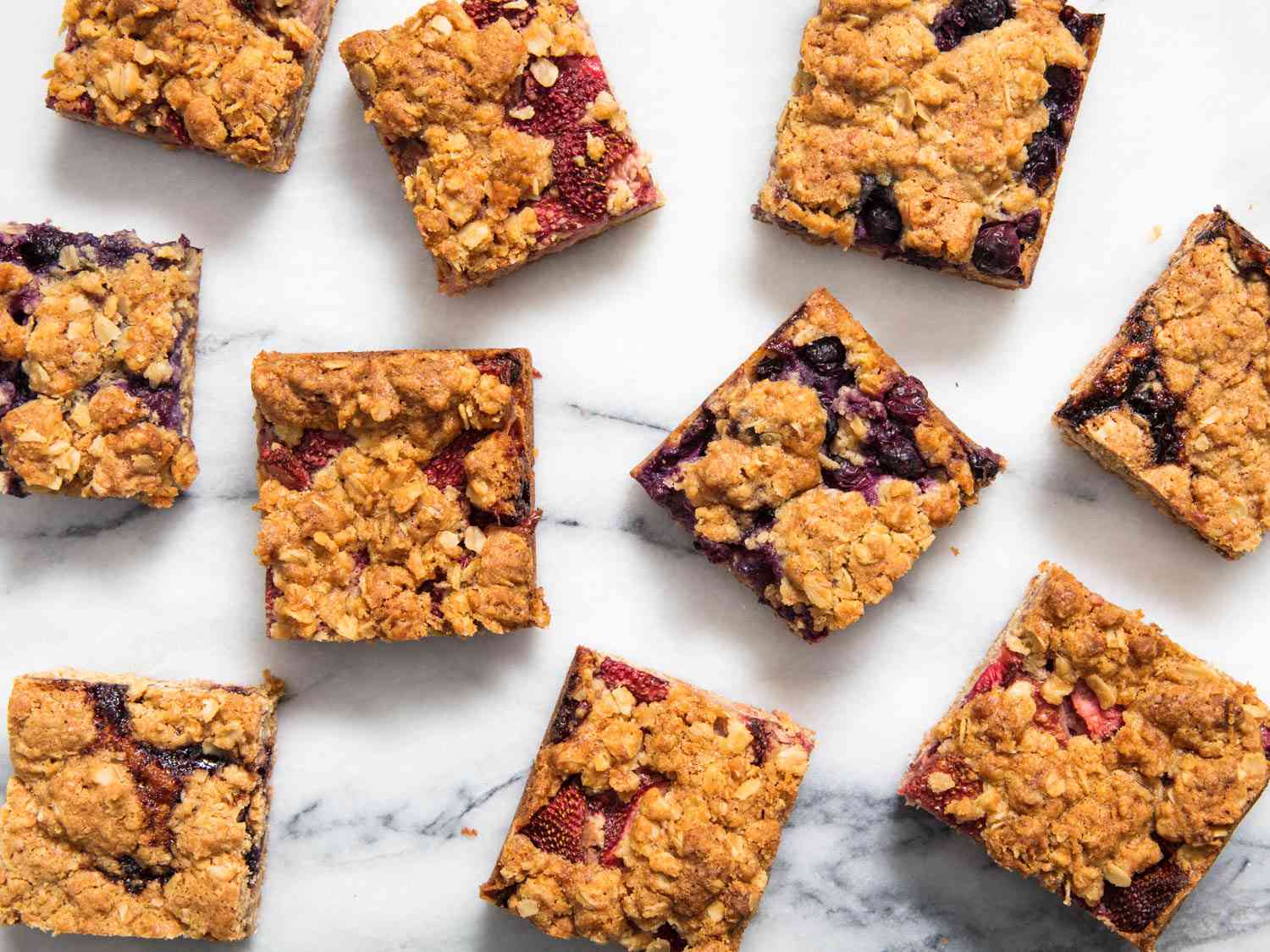 Top down view of jammy fruit bar squares on a marble surface.