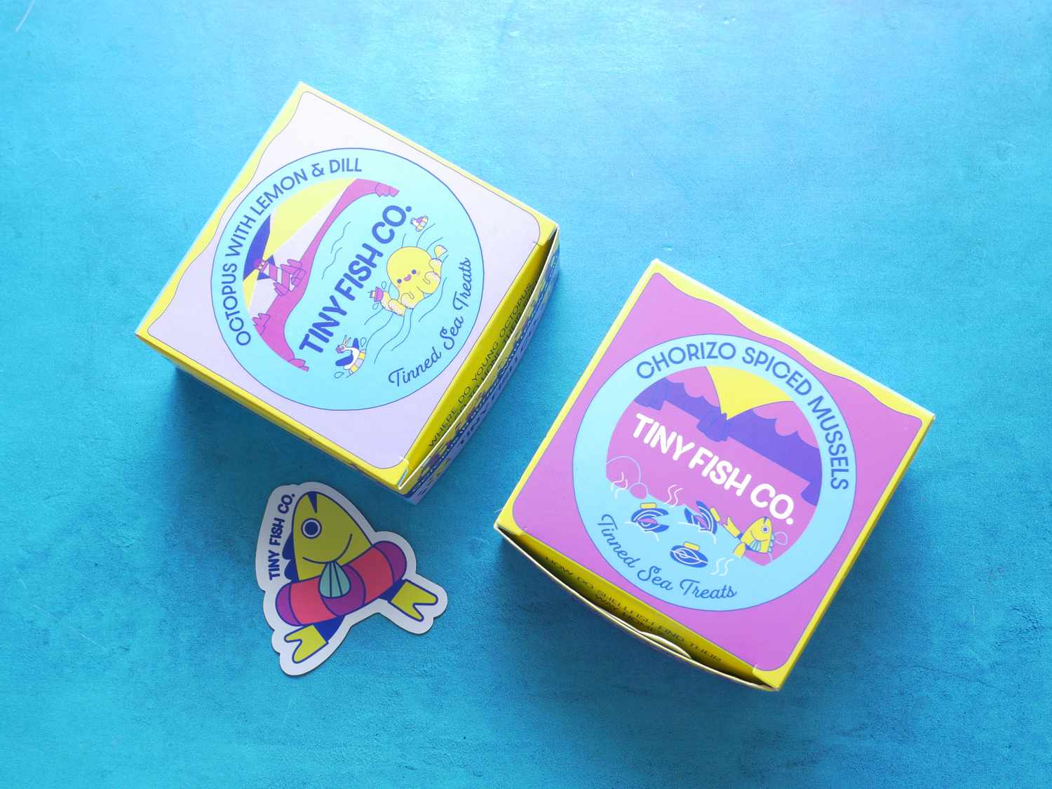 two tiny fish tins on a blue backdrop 