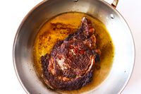 Cooked steak in a frying pan with oil