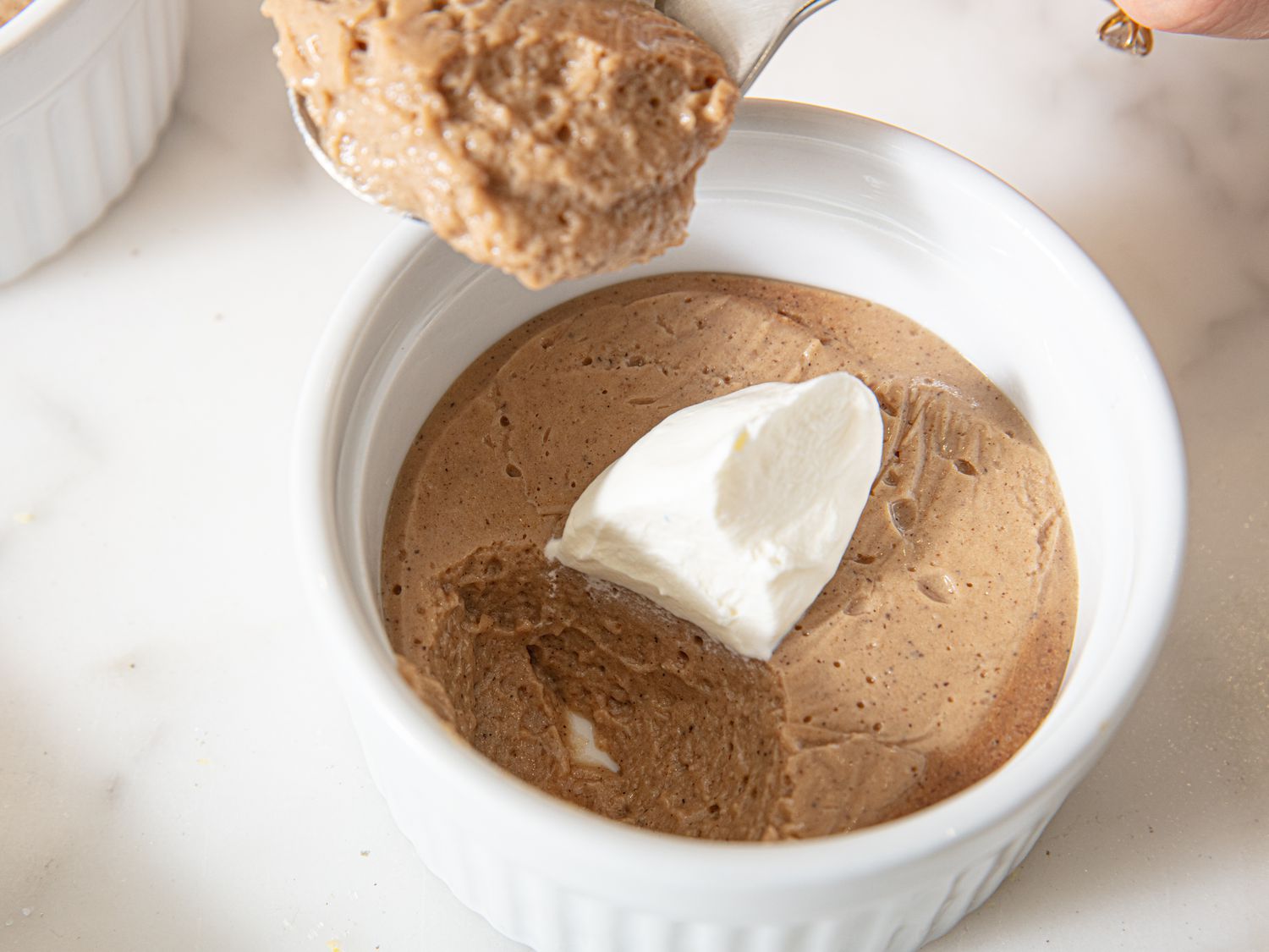 A ramekin of dessert with a dollop of whipped topping being spooned into