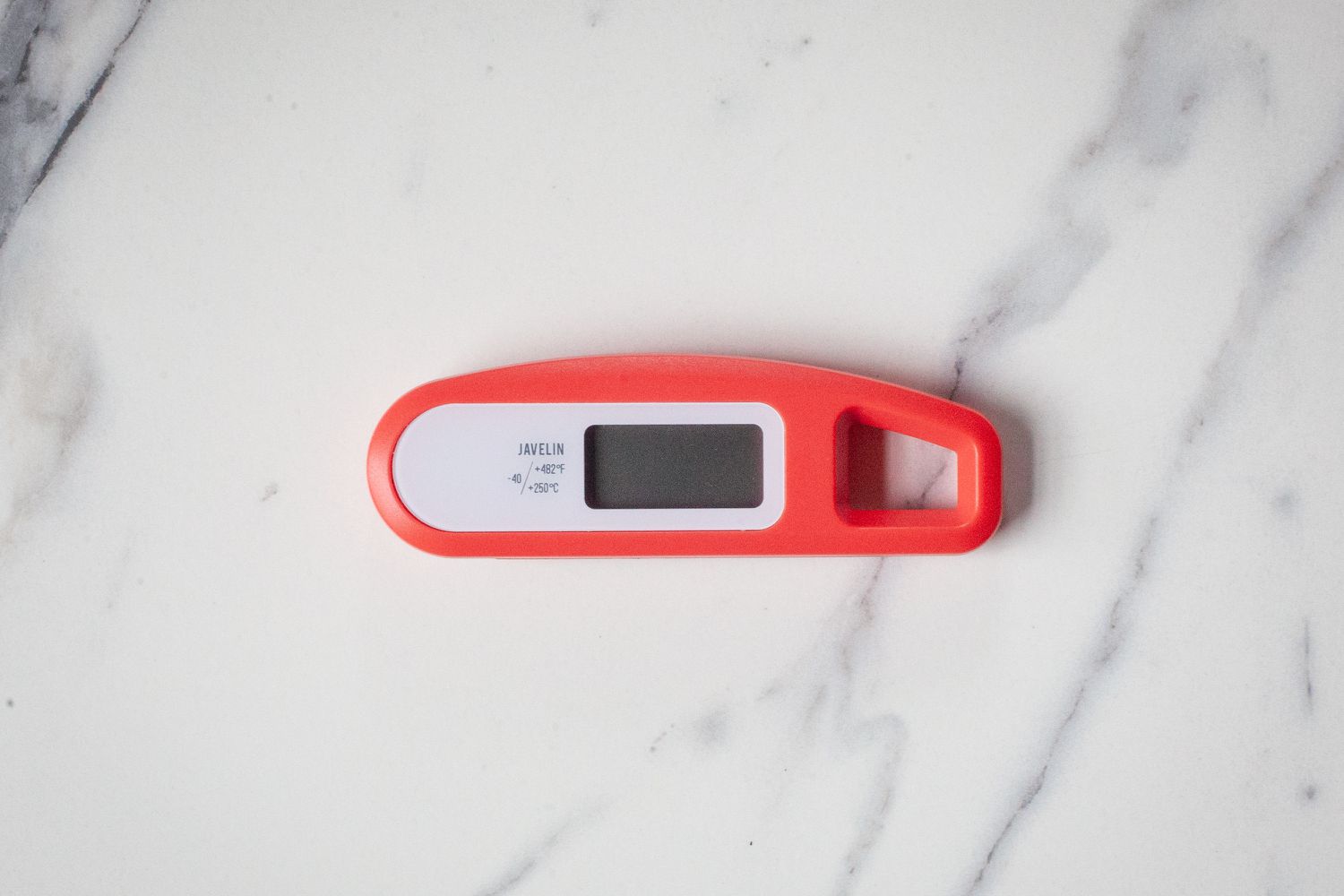 A red thermometer on a marble countertop.
