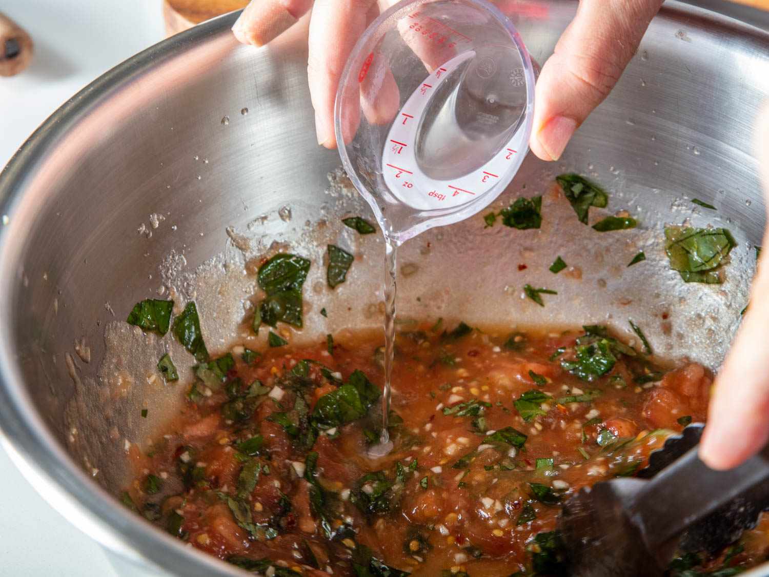 Adding pasta cooking water to sauce for Sicilian-style spaghetti alla carrettiera.