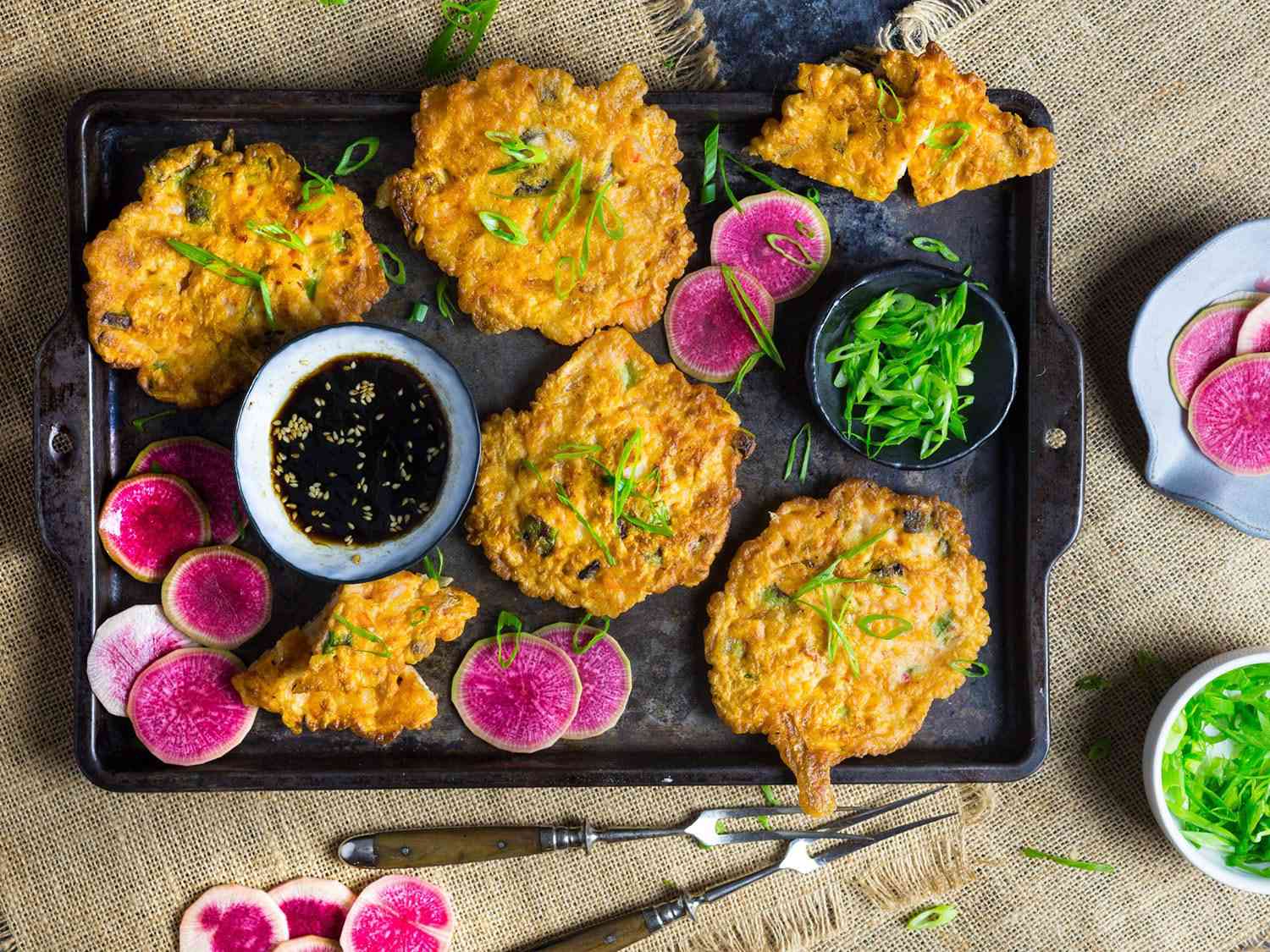 Overhead photo of kimchi pancakes on serving platter with watermelon radish and dipping sauce.