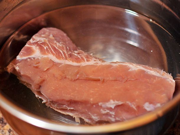 Cured pork loin submerging in water. 