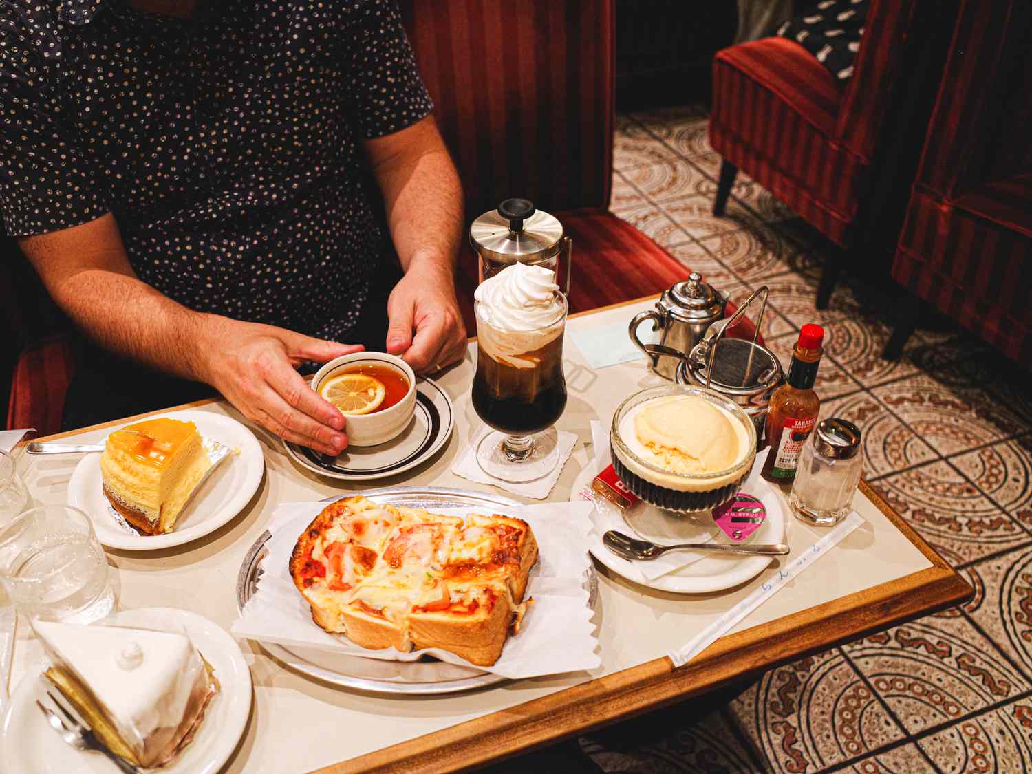 A table set with various pastries desserts and beverages including coffee ice cream and layered cake in a casual dining setting