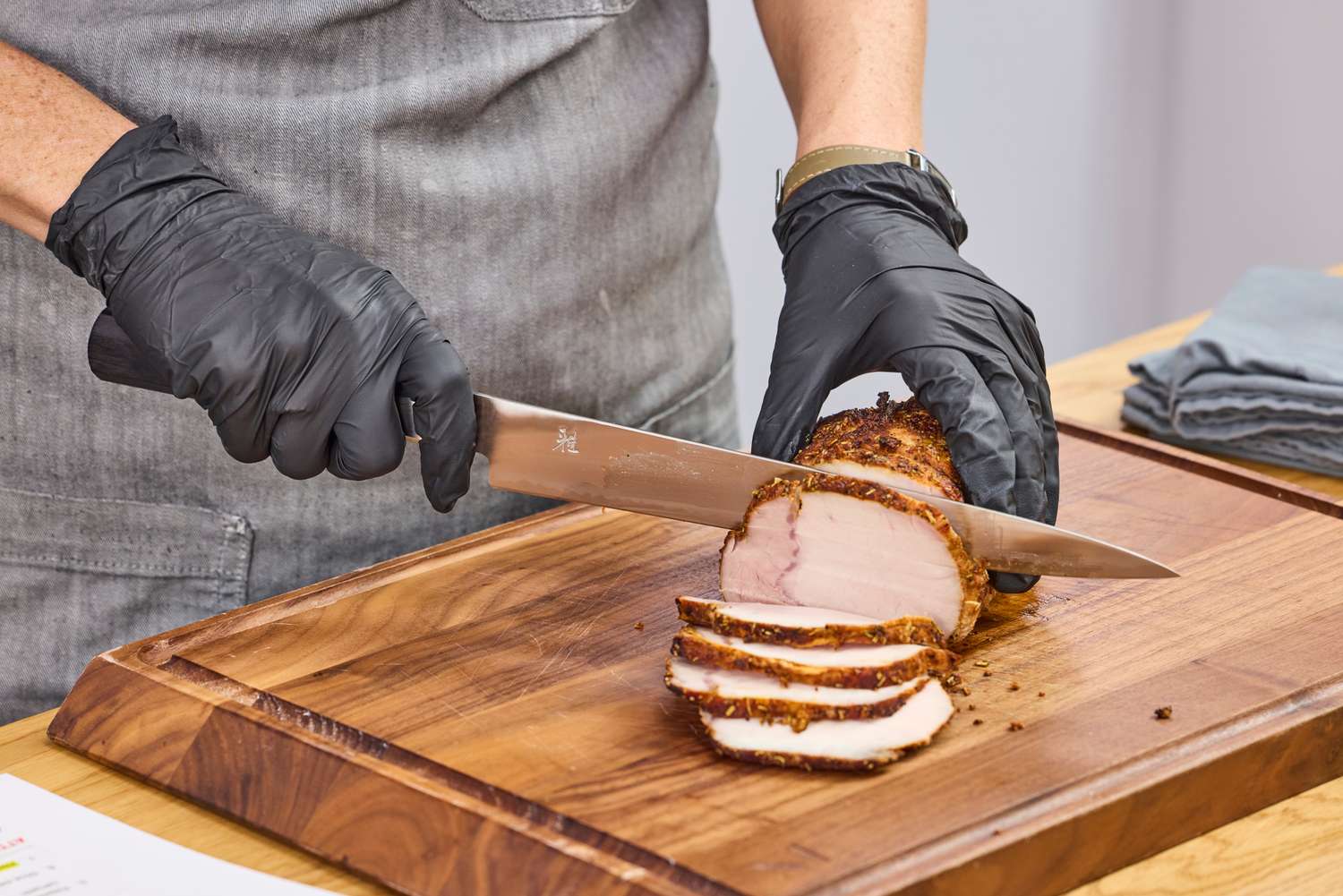 A person slices meat using the Miyabi Koh 9.5 Inch Slicing Knife