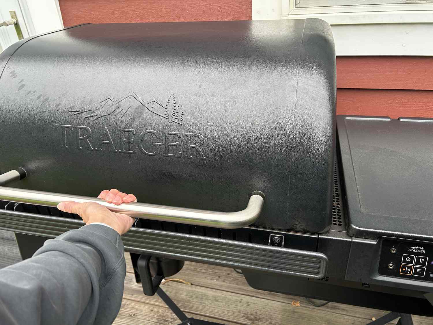A person lifting the lid of the Traeger Woodrige pellet grill
