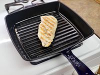 A pork chop cooking on the Staub Enameled Cast Iron Grill Pan