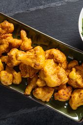 Cauliflower Pakoras next to a green chutney sauce