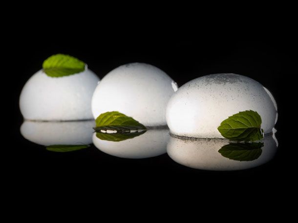 Carbonated mojito spheres garnished with mint leaves.