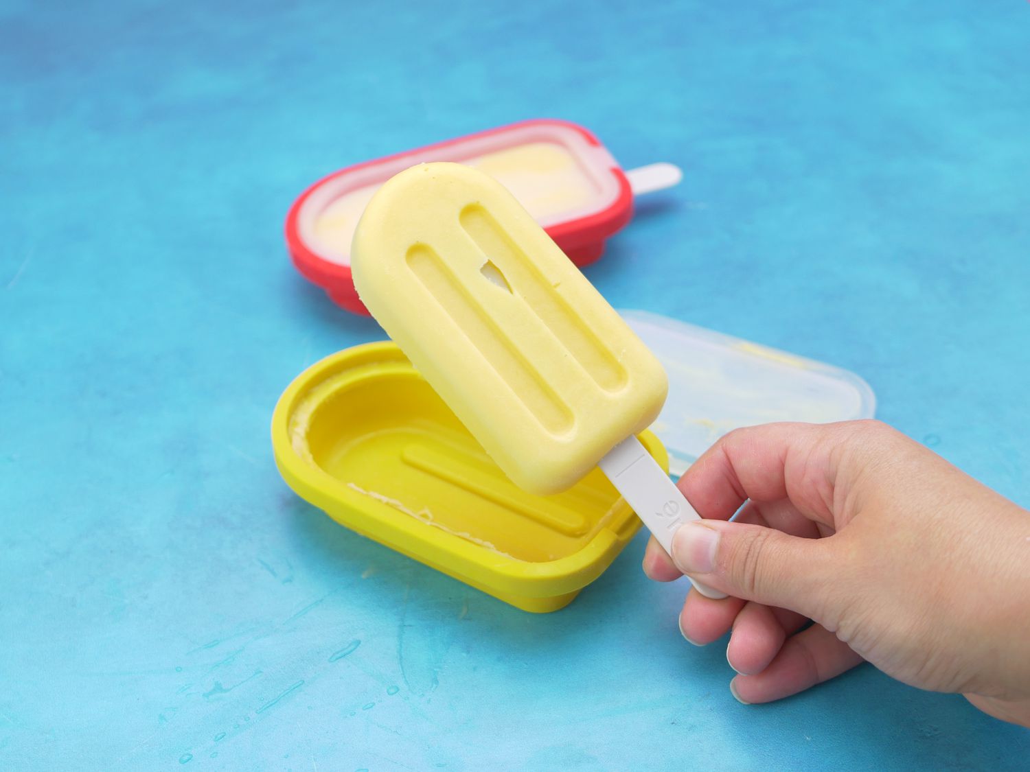 a hand holding a popsicle from a silicone mold