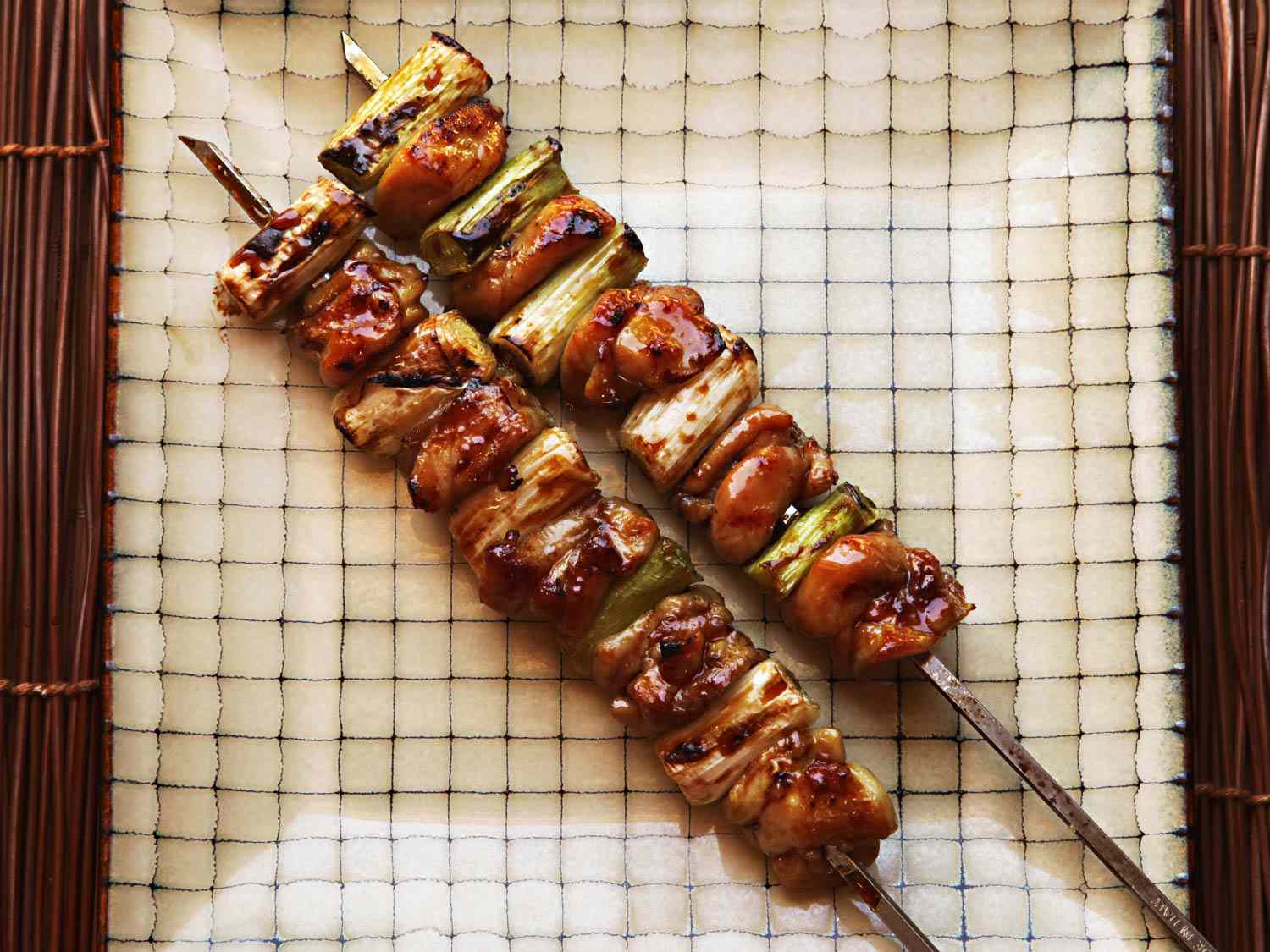 Overhead view of two teriyaki-marinated negima yakitori skewers.