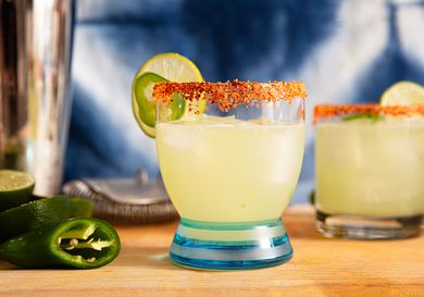 A spicy margarita cocktail garnished with a tajin rim and lime